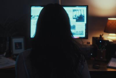 The back of a woman looking at her computer screen